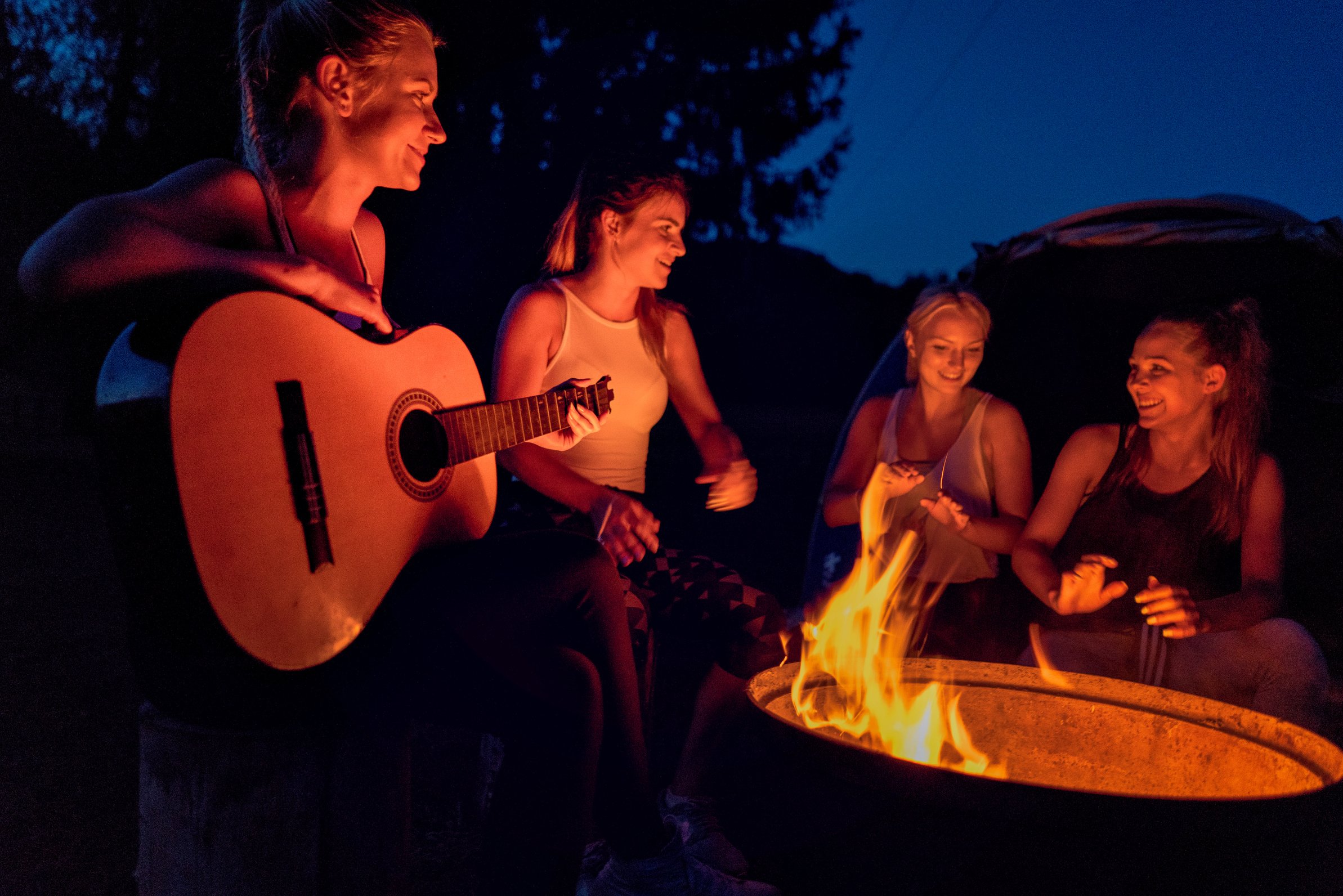 Friends enjoying music near campfire